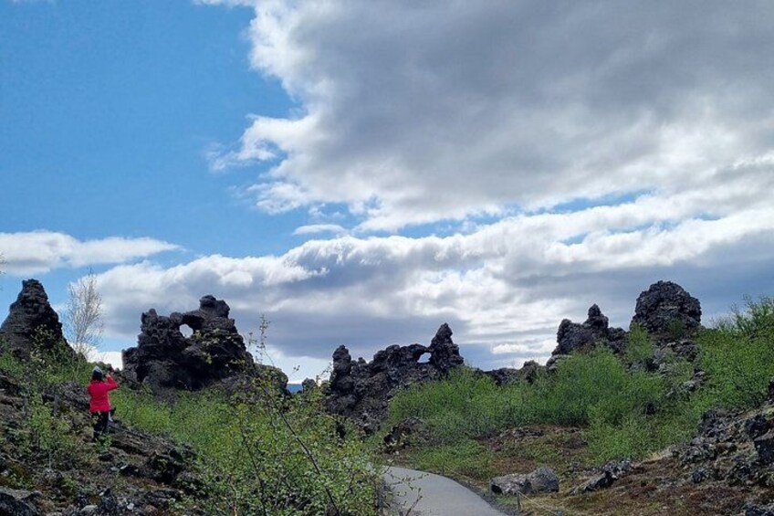 A rocky landscape with a person in a pink jacket, a clear sky, and scattered clouds. 4