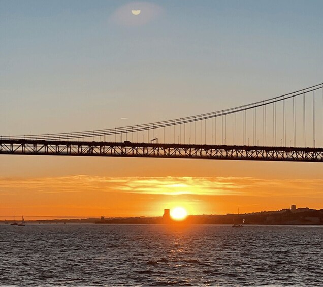 A bridge over water during sunset with the sun visible near the horizon. 4