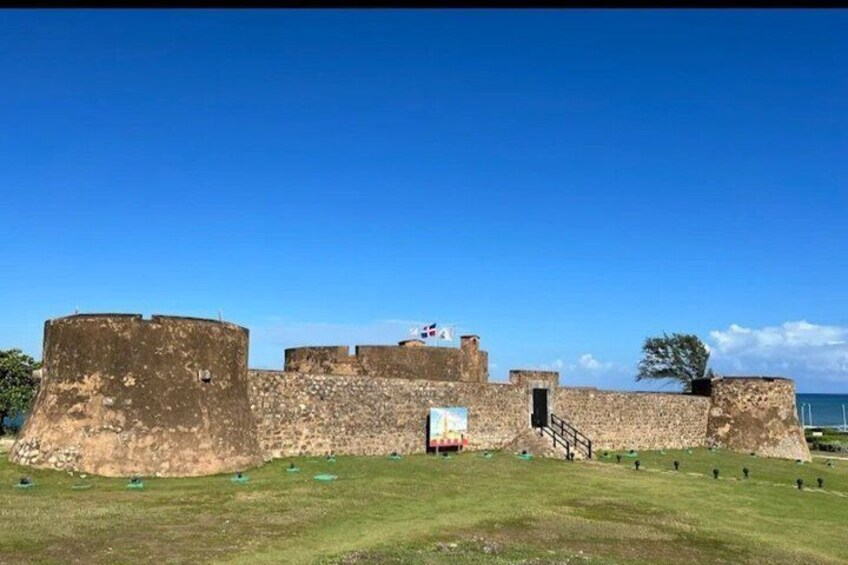 A historical fort with large stone walls, a staircase leading to a door, and a clear blue sky. 4