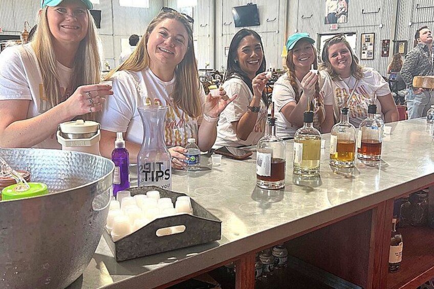 A group of people at a bar with various bottles and a large metal container. 3