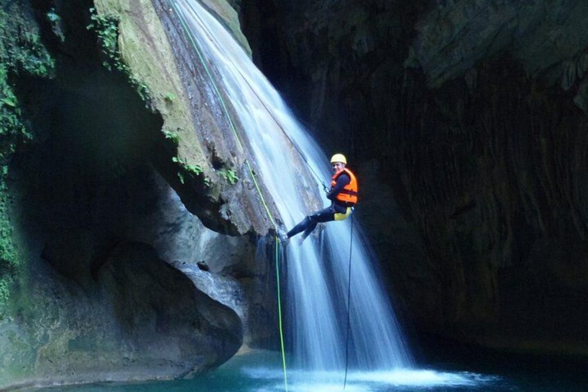 A person rappelling down a waterfall in a rocky canyon. 3