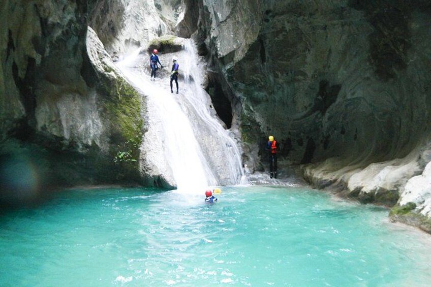 A waterfall, a person in a kayak, and three people climbing a rock face. 2