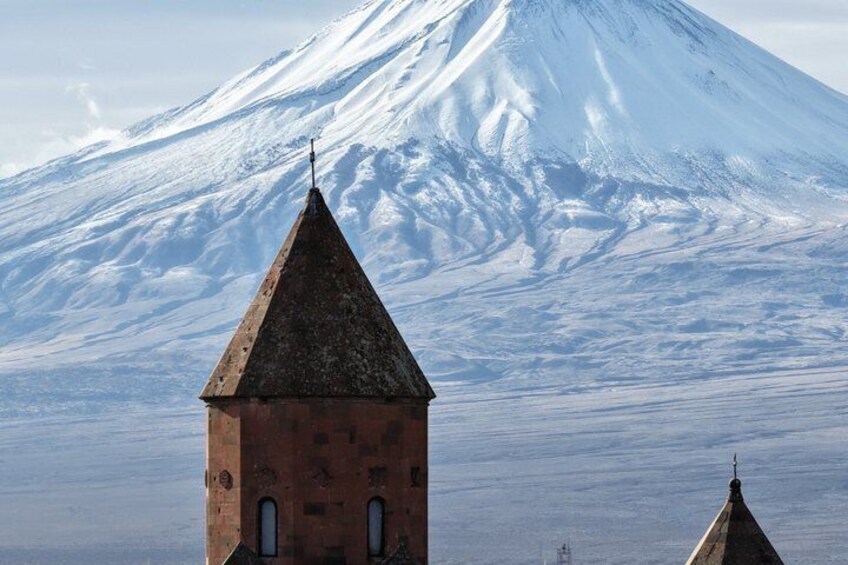 Ett snötäckt berg med ett kyrktorn i förgrunden. 4