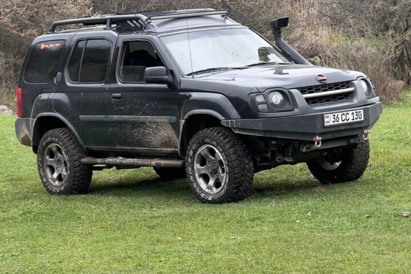 En svart SUV med terrängdäck parkerad på gräset. 2