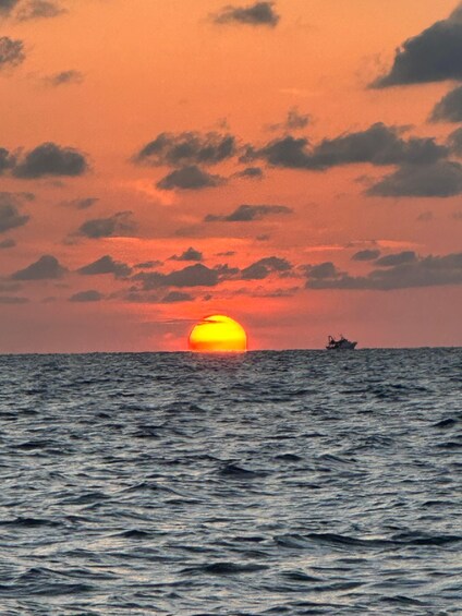 A sunset over the ocean with a ship in the distance. 3