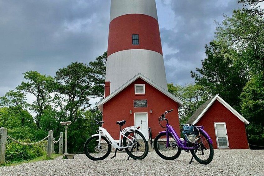 A red and white lighthouse with two bicycles parked in front. 4