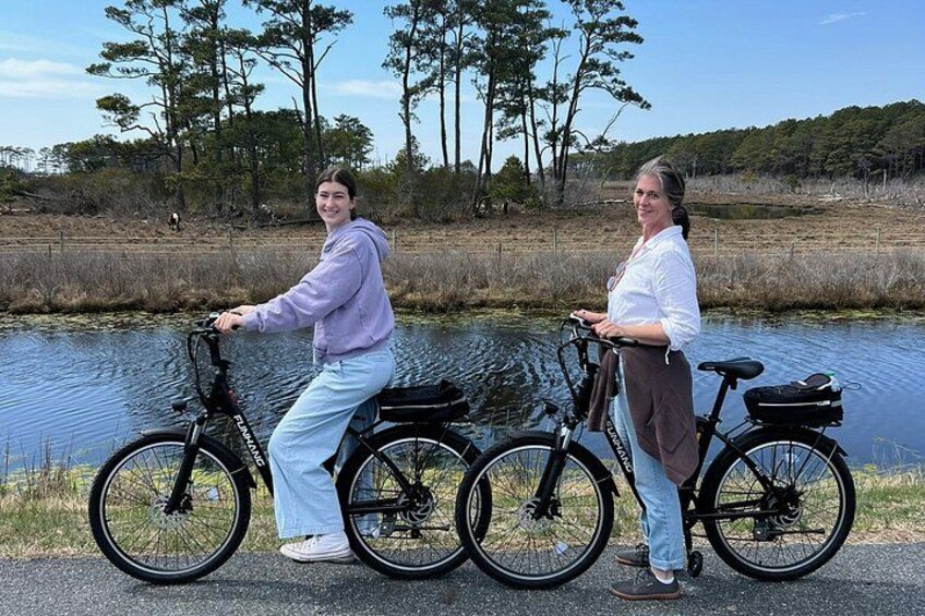 Two people standing by a body of water with bicycles. 3