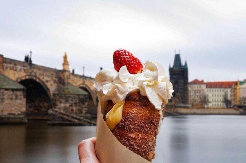 Un dessert con panna montata e una fragola, fotografato con sullo sfondo un ponte storico. 1