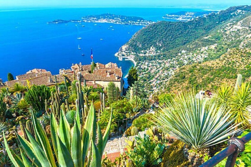 A coastal town with a prominent building, lush greenery, and a view of the sea. 5