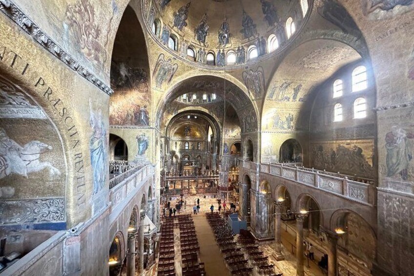 An interior of a grand cathedral with high vaulted ceilings, intricate frescoes, and rows of pews. 5
