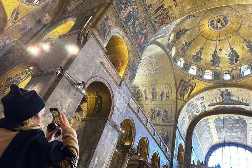 An interior of a grand building with a domed ceiling, intricate frescoes, and arched doorways. 3