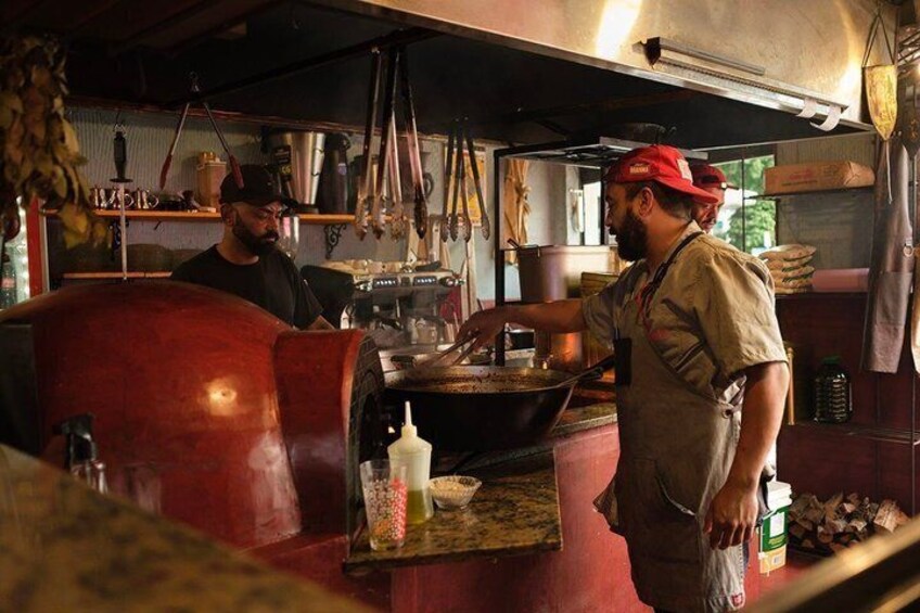 Una cocina con un horno rojo, una persona cocinando y diversos utensilios de cocina. 5
