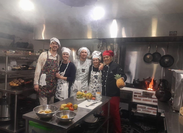 A group of chefs in a kitchen with stainless steel surfaces, pots, and a fire. 4