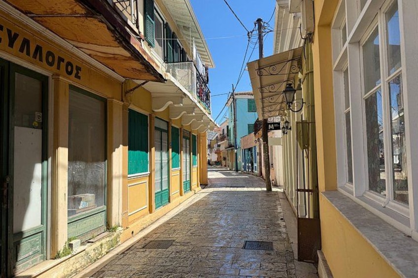 A narrow cobblestone street lined with colorful buildings, a clear blue sky, and a sign reading 'ΕΛΛΑΓΟΕ'. 5