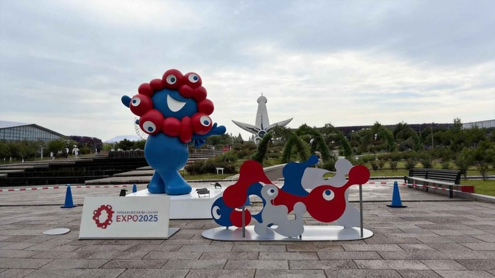 A blue and red mascot sculpture, a white and red abstract sculpture, and a sign for EXPO2025. 5