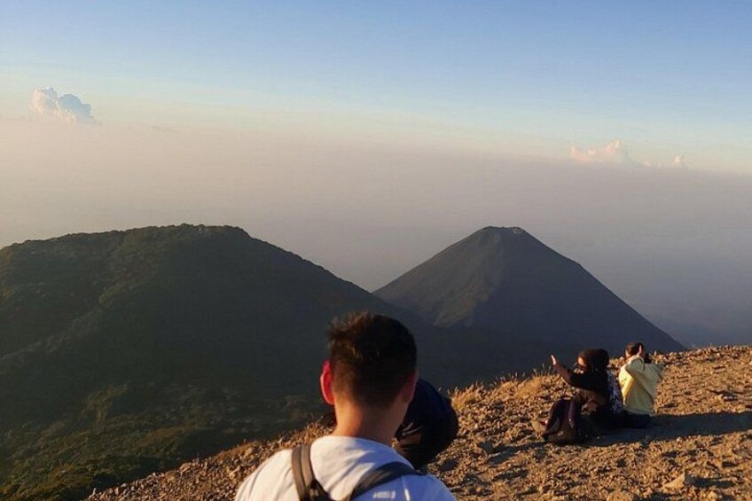 Un grupo de personas en una cresta montañosa, con vistas a dos picos. 3