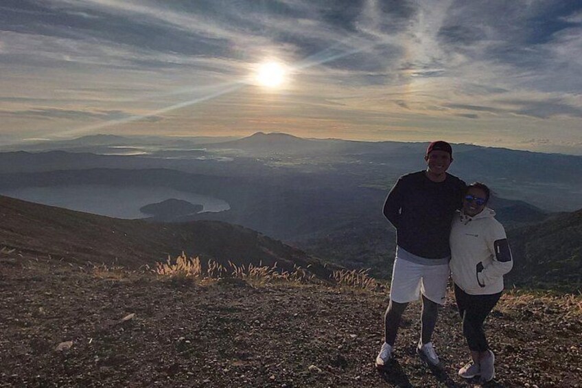 Dos personas de pie en la cima de una colina, con un lago y montañas al fondo. 2