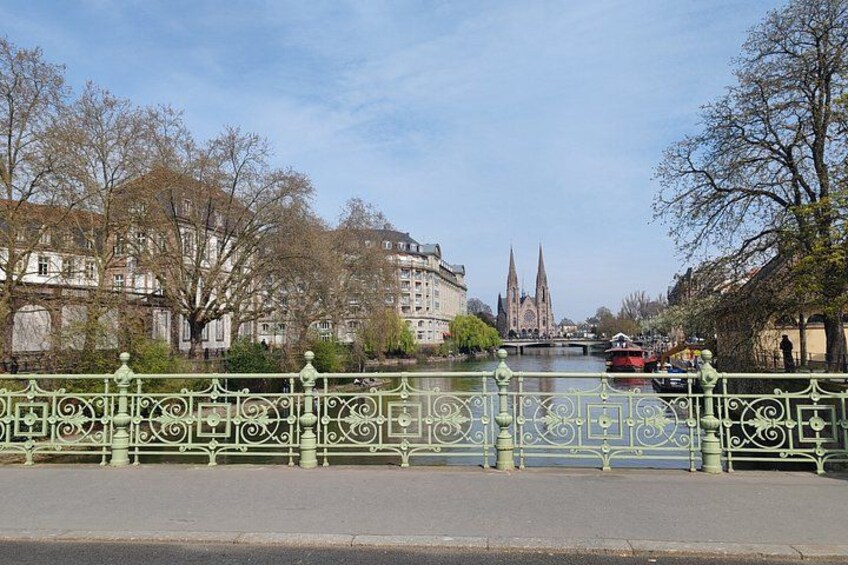 Un río con un puente, edificios y la aguja de una iglesia al fondo. 3