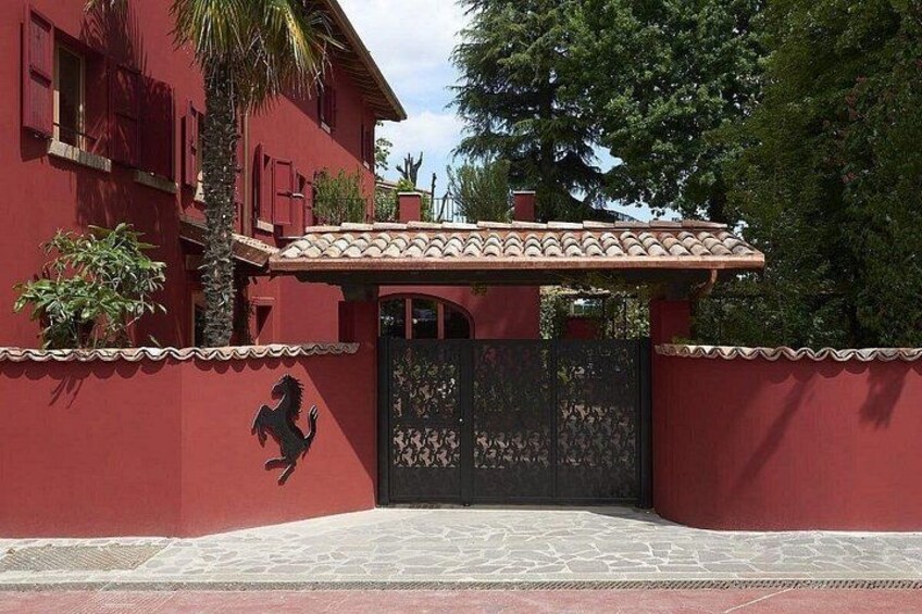 Un bâtiment rouge avec un portail noir, un palmier et un mur décoratif. 4