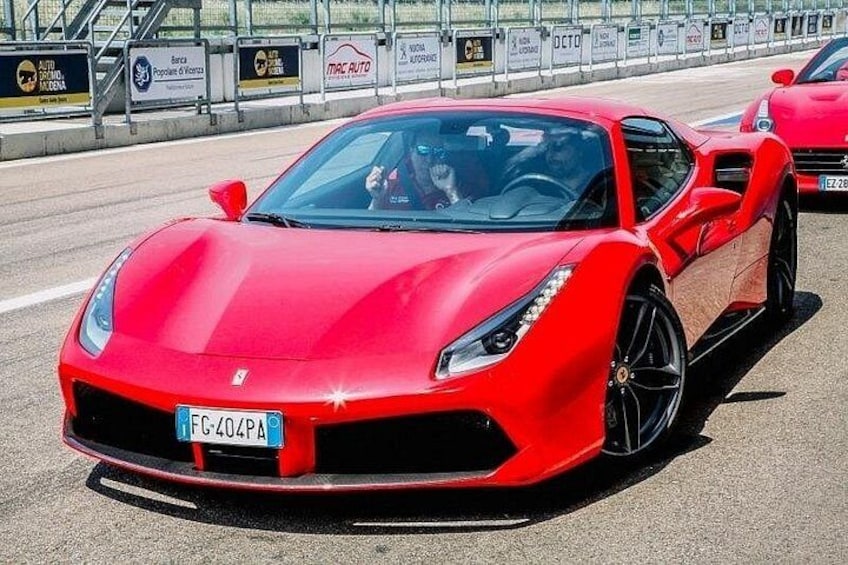 Une voiture de sport rouge sur un circuit de course, avec une plaque d’immatriculation portant le numéro FC-404PA. 5