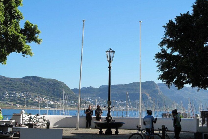 A waterfront promenade with a lamp post, bicycles, and people. 3