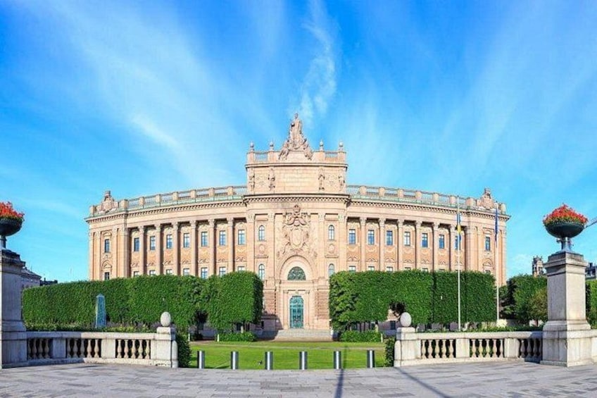 A large, ornate building with a central dome and symmetrical design, surrounded by a well-maintained garden and a paved walkway. 2