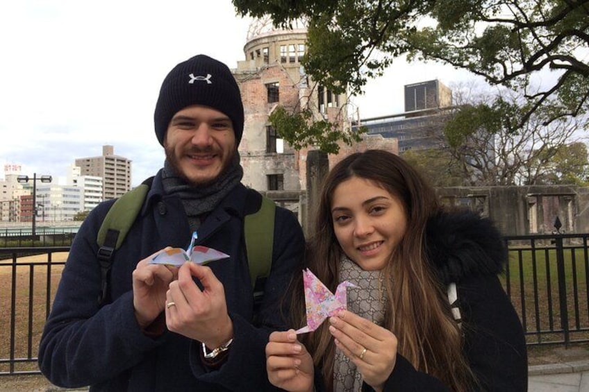 Two people holding colorful kites in an urban park with buildings in the background. 1