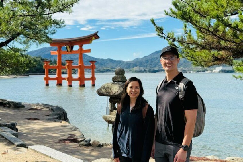 Una pareja de pie junto a un torii japonés tradicional con un farol de piedra y un lago pintoresco al fondo. 3