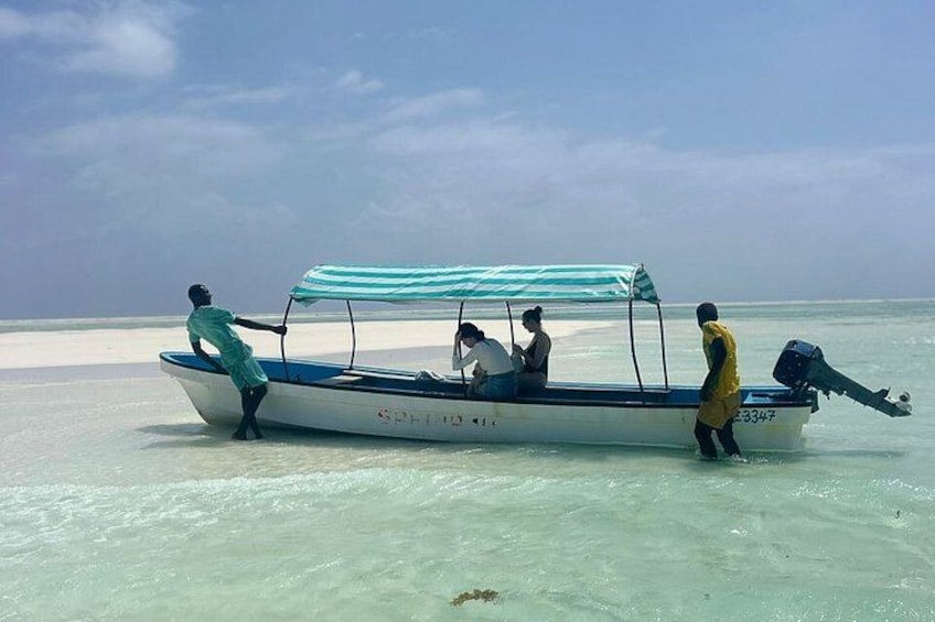 Ein Boot mit einem gestreiften Sonnensegel, an Bord befinden sich Personen und das Wasser ist ruhig. 4