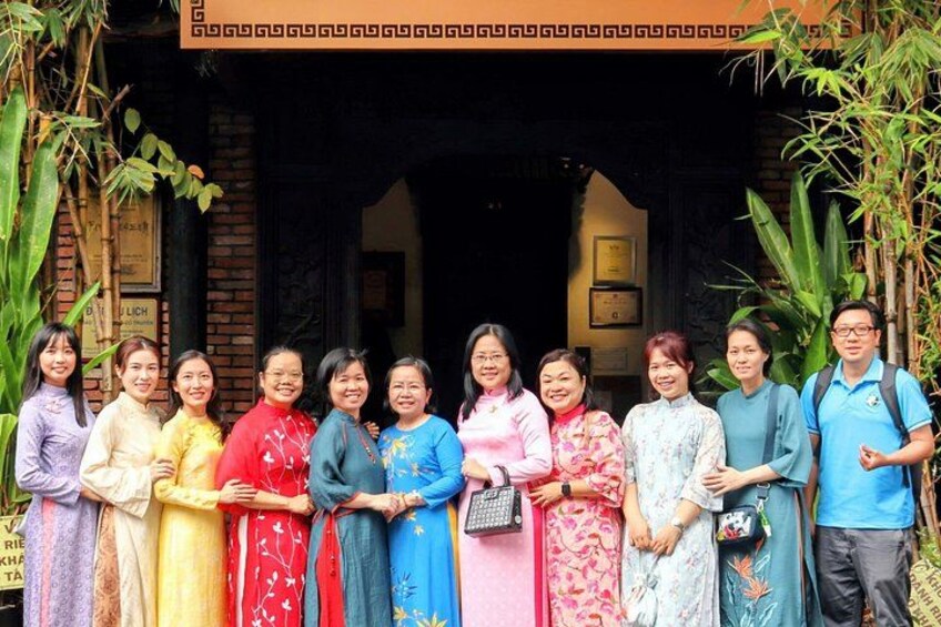 Un groupe de personnes se tient devant un bâtiment traditionnel dont l’entrée est ornée de motifs décoratifs. 4