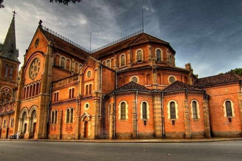 Un grand bâtiment en briques, doté de nombreuses fenêtres en arc de cercle et d’une tour horloge. 1