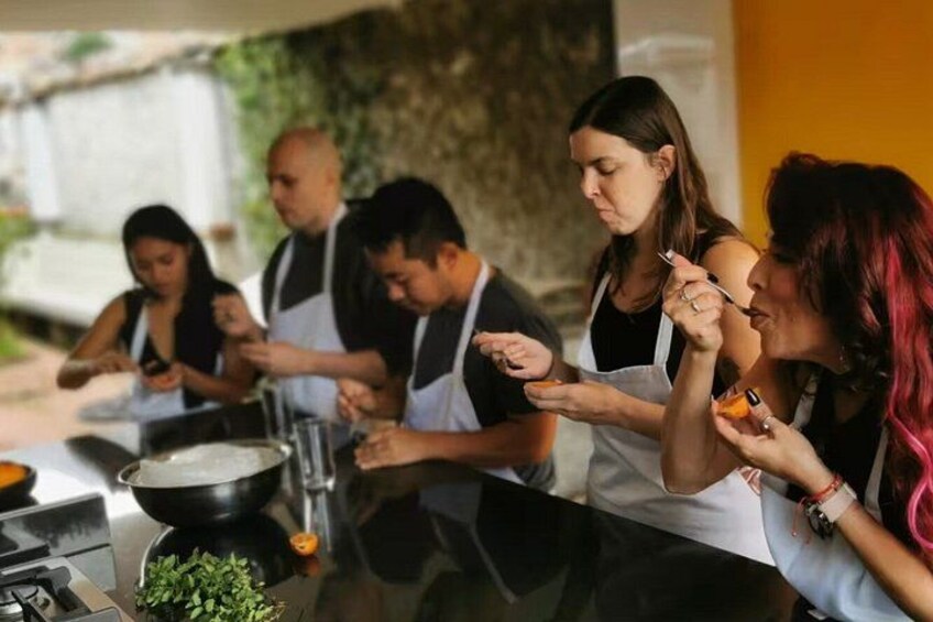 A group of people cooking outdoors, with a pot on the stove and ingredients on the table. 2