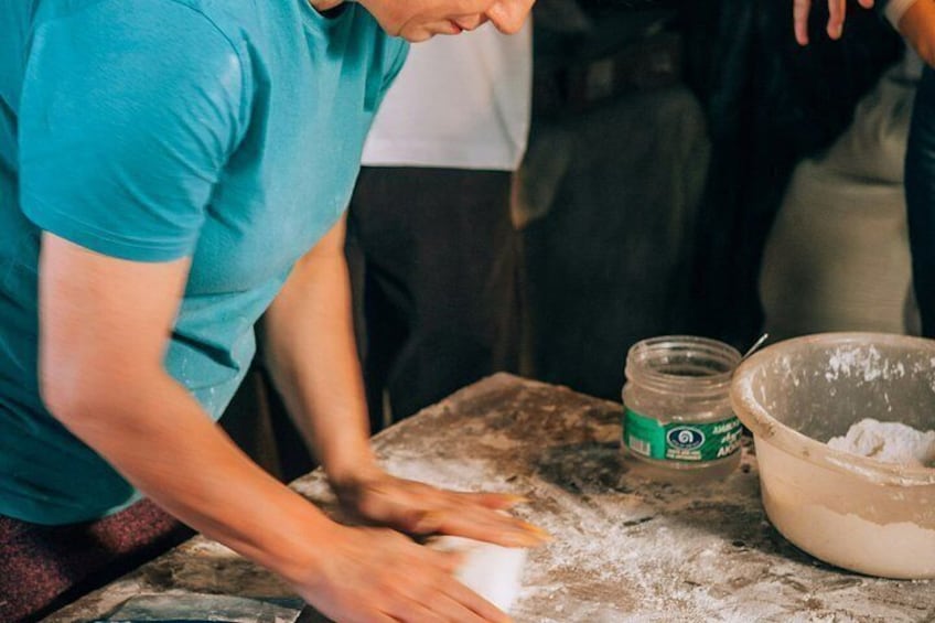 A person kneading dough on a flour-dusted surface with a bowl and a jar nearby. 2