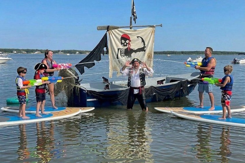 People on paddleboards, a pirate-themed tent, and a body of water. 1