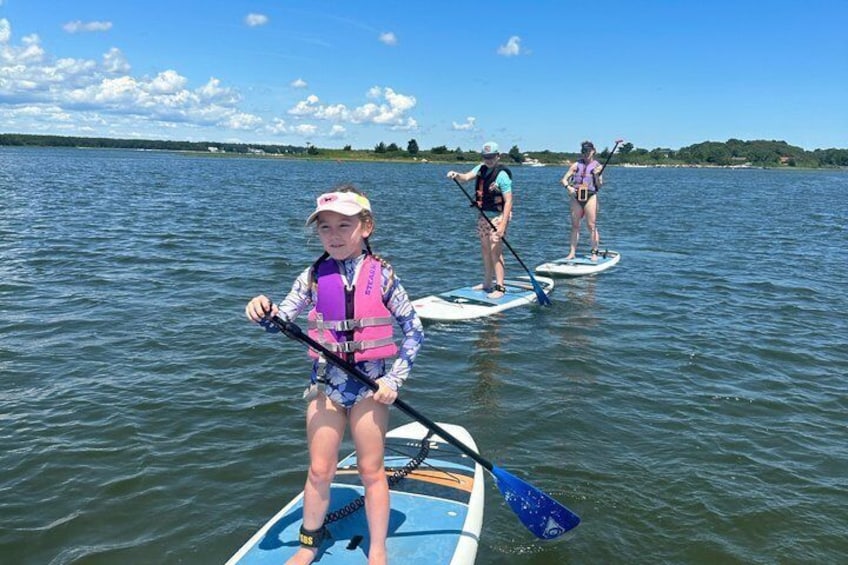 Three people paddleboarding on a calm lake with a clear sky. 3