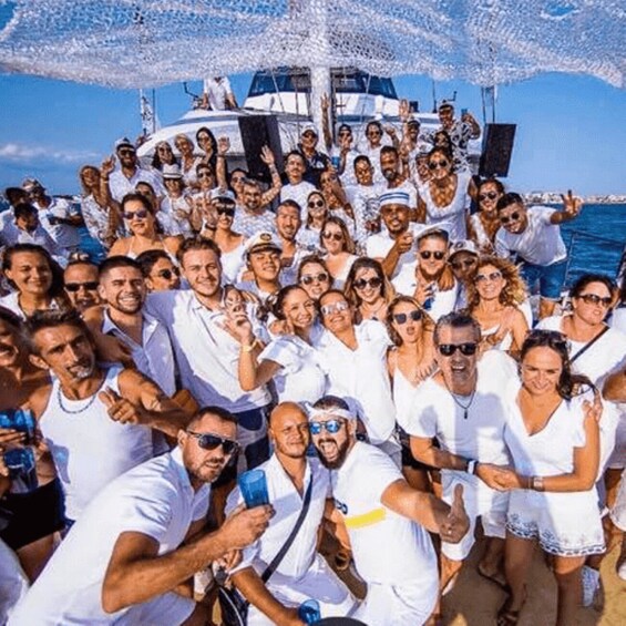 A group of people on a boat, wearing white, with a clear blue sky in the background. 2