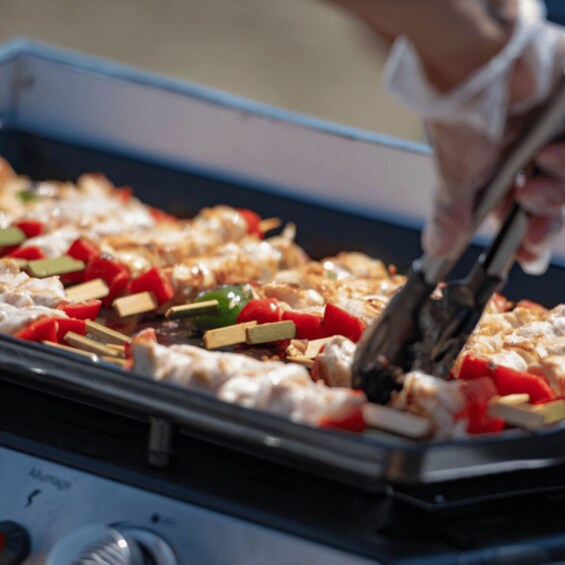 A person grilling vegetables and meat on a grill. 3