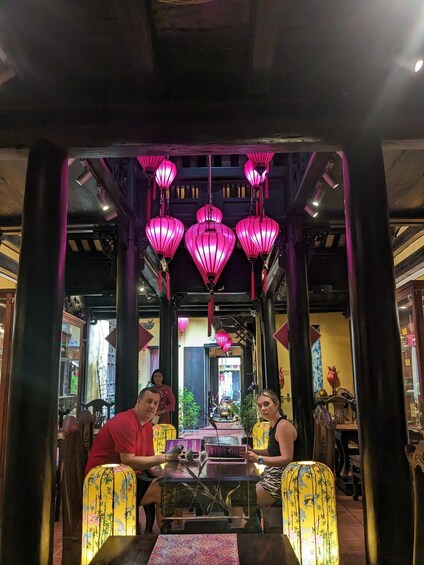 A restaurant interior with traditional decor, including hanging pink lanterns and wooden furniture. 3