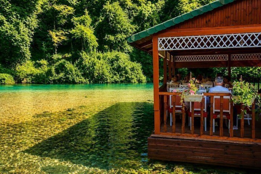 Een houten tuinhuis aan een meer met helder water, omringd door weelderige groene bomen. 4
