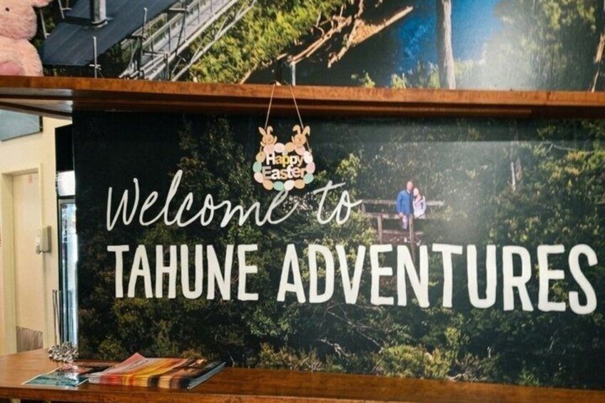 Un letrero de bienvenida para Tahune Adventures, con un bosque de fondo. 1