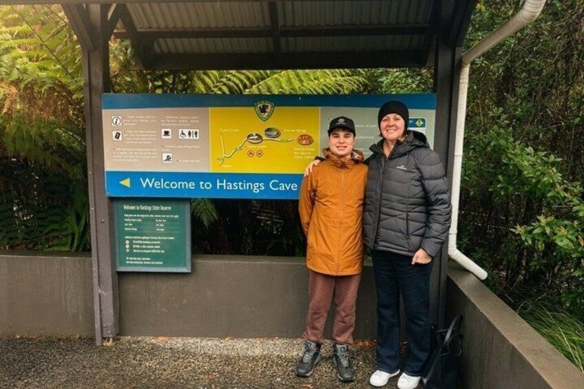 Dos personas de pie frente a un letrero que dice 'Welcome to Hastings Cave'. 2