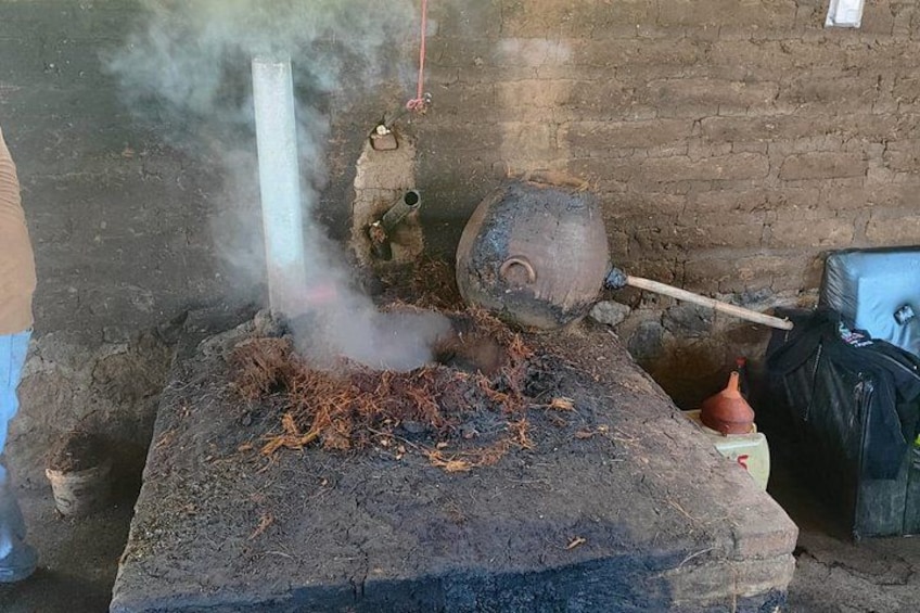 Un dispositif de cuisson traditionnel comprenant un grand pot en argile, un récipient en métal et une cheminée qui dégage de la fumée. 1