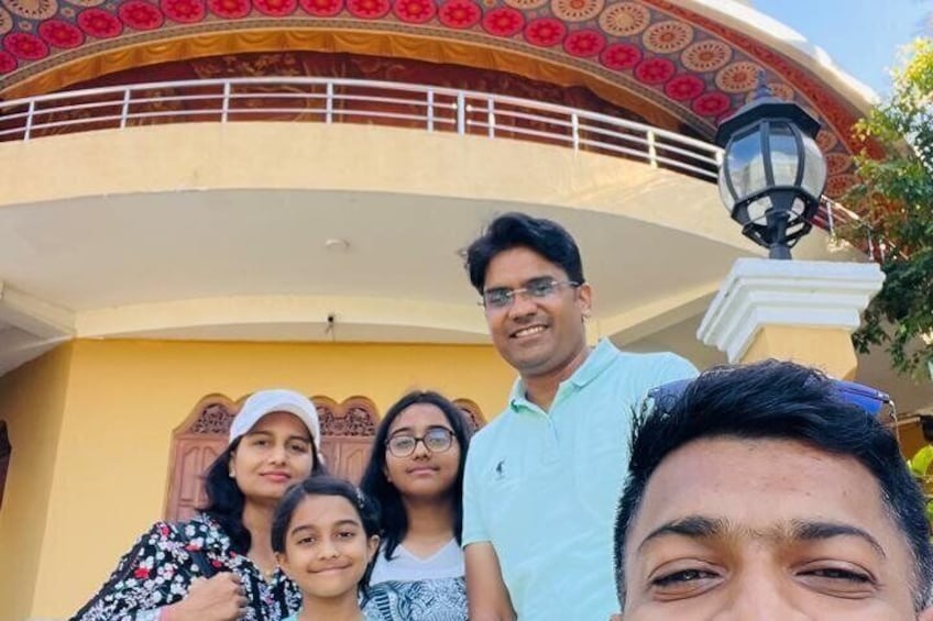 A family in front of a building with a decorative archway and a street lamp. 1
