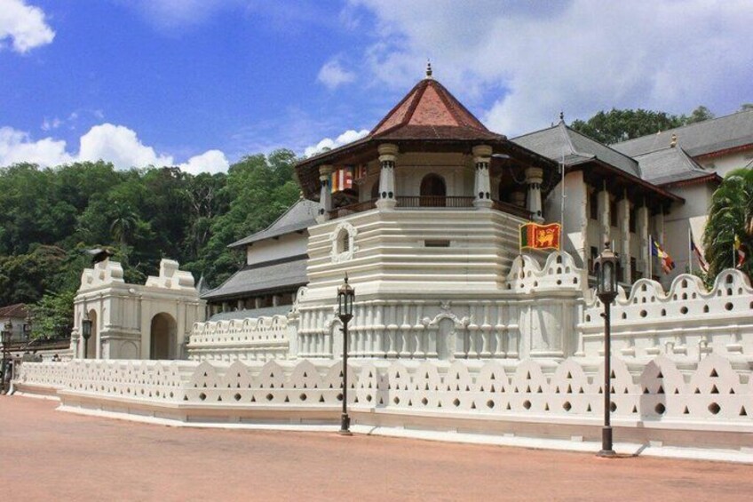 A white colonial-style building with a red roof, surrounded by a white wall with decorative elements. 5
