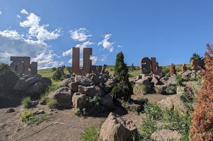 Large stone letters scattered on a hillside with a clear sky. 2