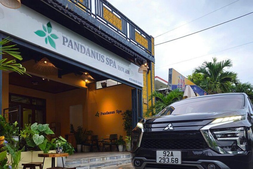 En byggnad med en skylt som visar texten ”PANDANUS SPA HOLAN ”. En svart bil står parkerad framför. 1