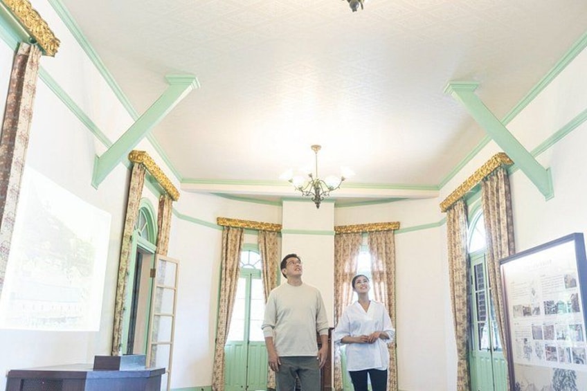 Una stanza con pareti verdi, un lampadario e tende. 1