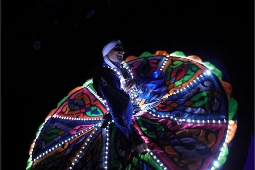 A person in a colorful, illuminated costume with a large, circular, patterned design. 3