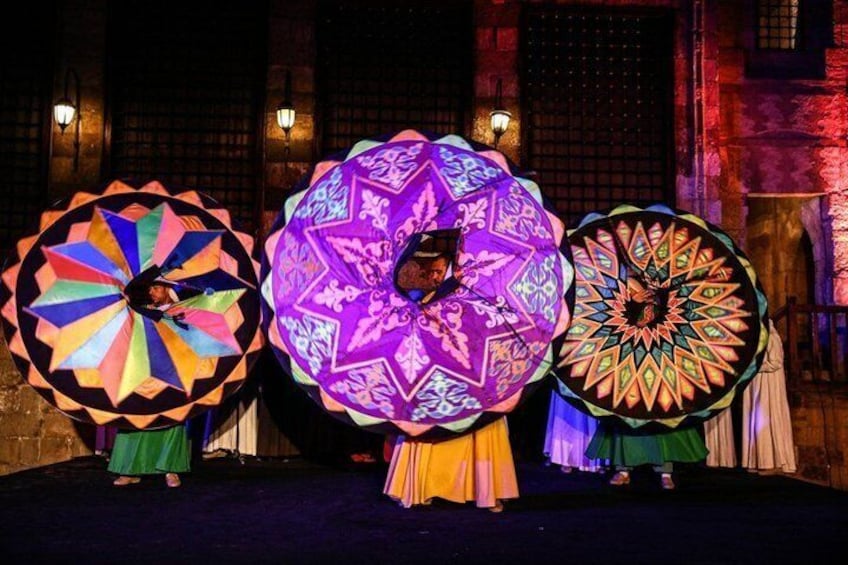 Three performers with large, colorful umbrellas on a stage. 2