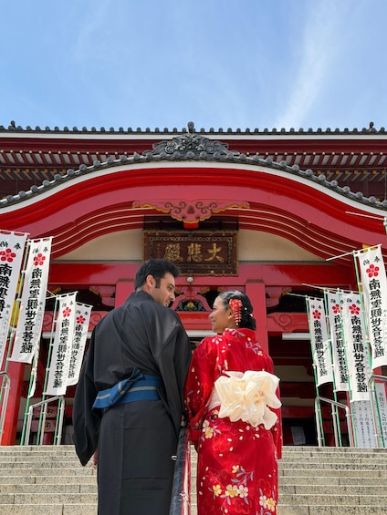 A traditional Japanese building with red and white walls, a tiled roof, and banners with Japanese characters. 2